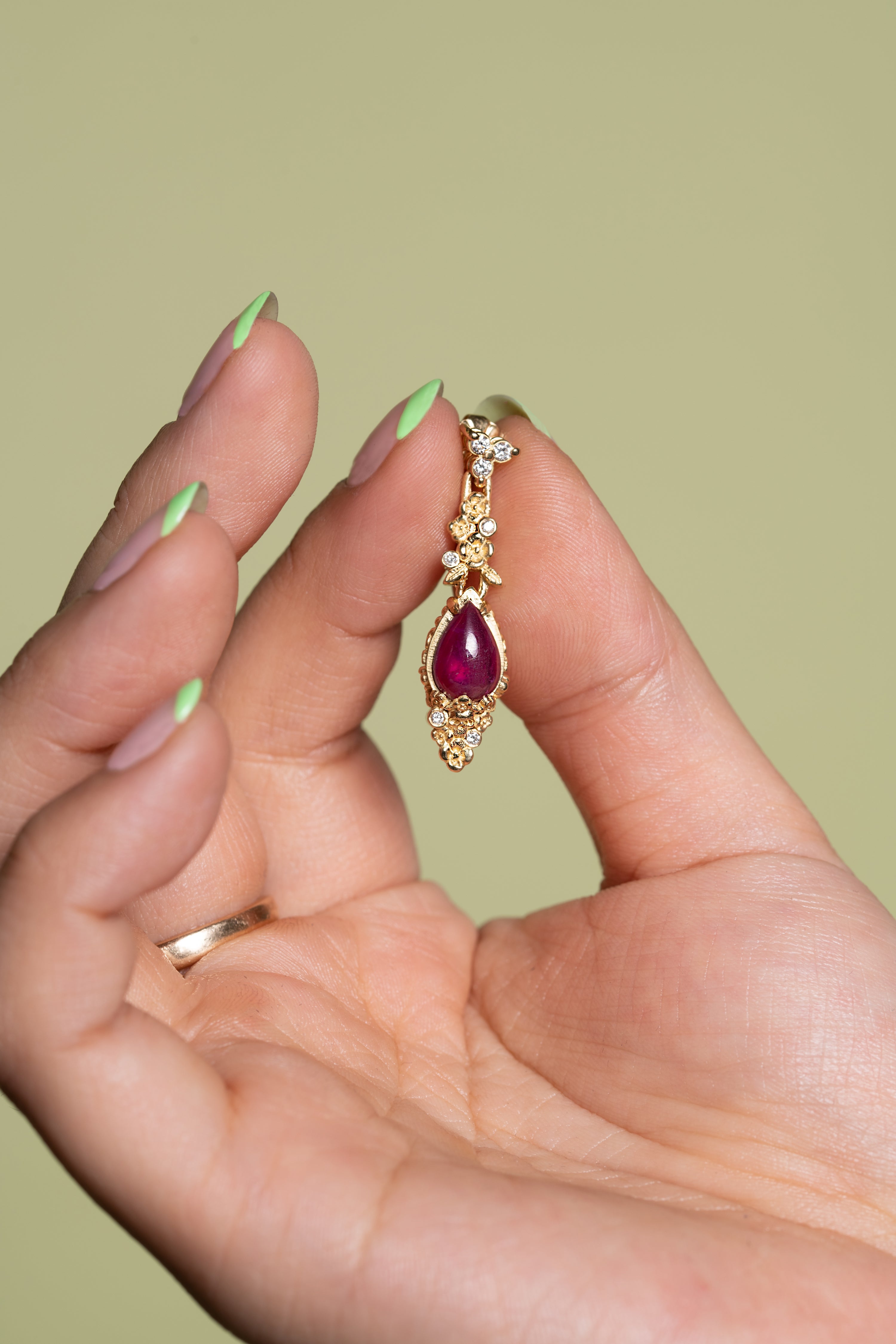 Model holds a single Ruby Skull Drop Earring