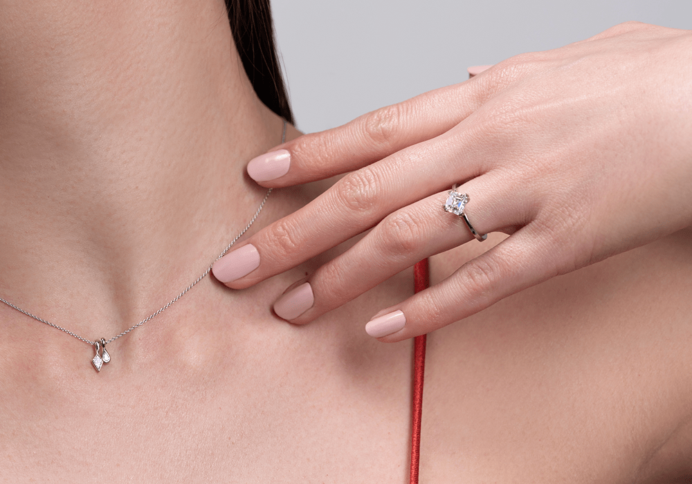 Model posing showing neck with our Diamond Duo / Pendant and left hand with our Ash / Asscher Cut Diamond Ring on ring finger