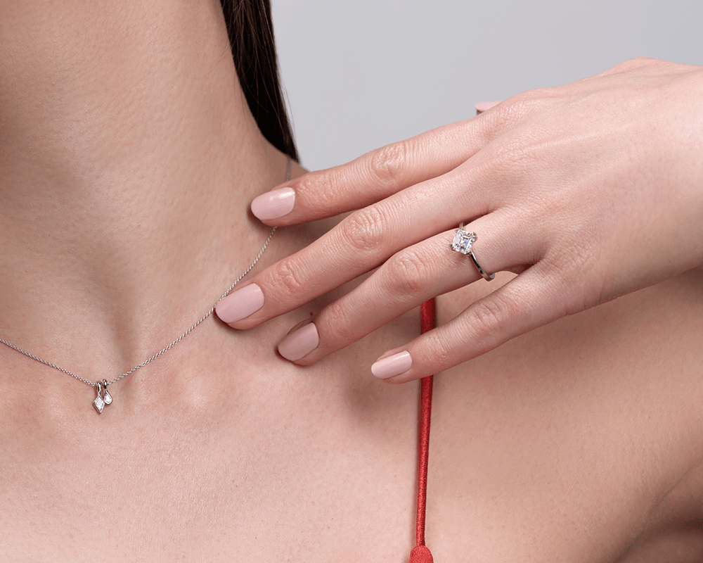 Model posing showing neck with our Diamond Duo / Pendant and left hand with our Ash / Asscher Cut Diamond Ring on ring finger