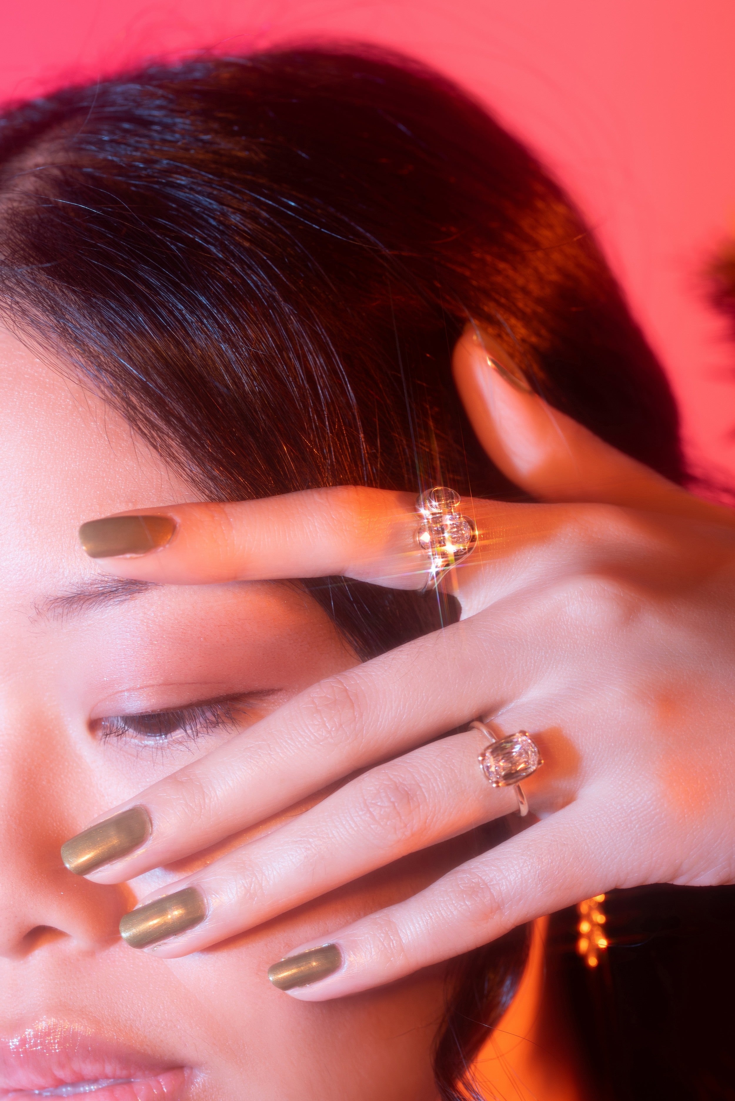 Close-up of a model with two engagement rings on a pink background
