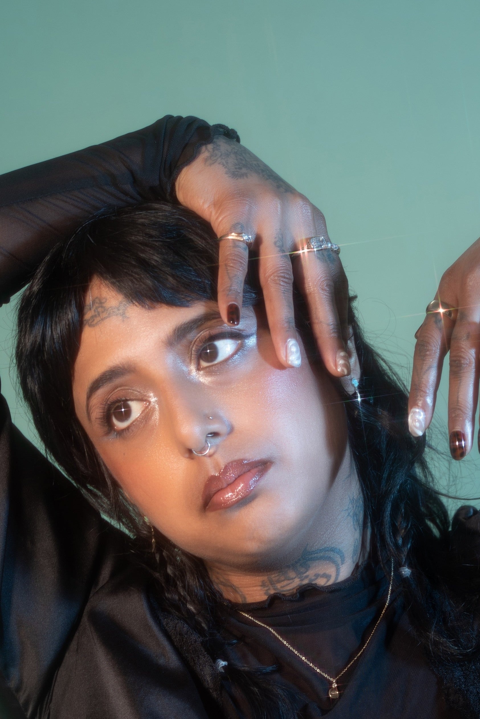 Person wearing a black outfit with sheer elements against a green background