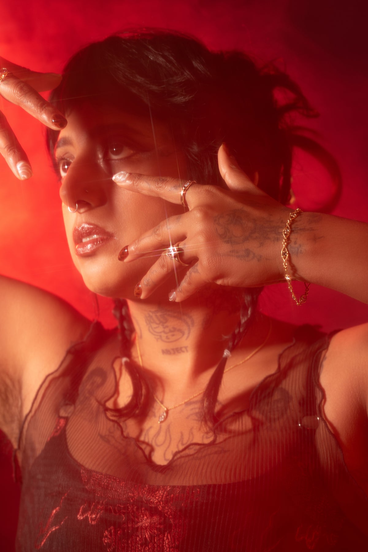 Model showcasing various fine jewelry items with hands posed with a dark red background
