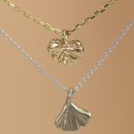 Lifestyle video showing Ginkgo Necklace in 14k white gold and Lotus Necklace in 14k yellow gold hanging together