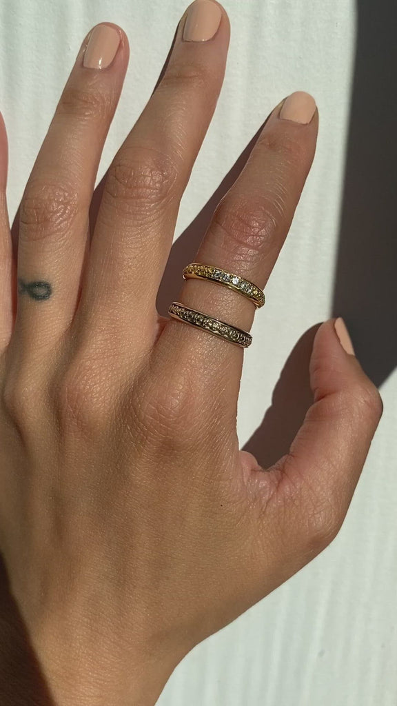 Model wears Skulls In A Line / 3.5mm in 18k white gold and Skulls In A Line / 5 White Diamond Ring in 18k yellow gold stacked on index finger	